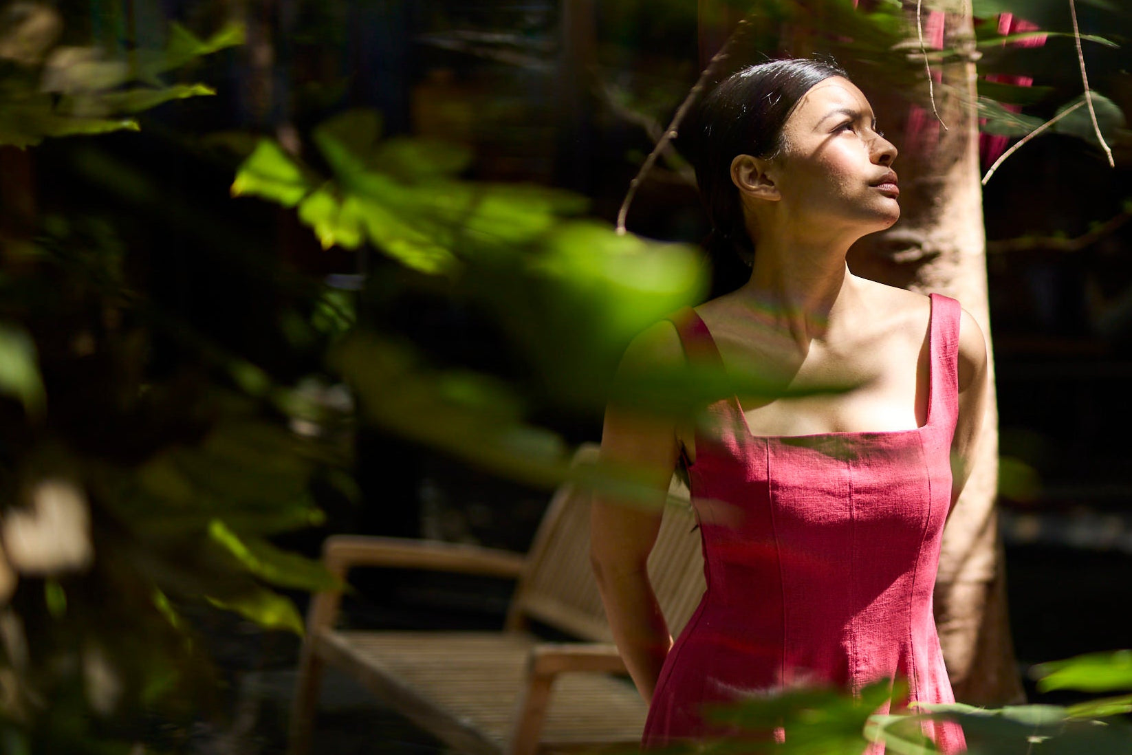 Woman in a pink dress standing among tropical plants